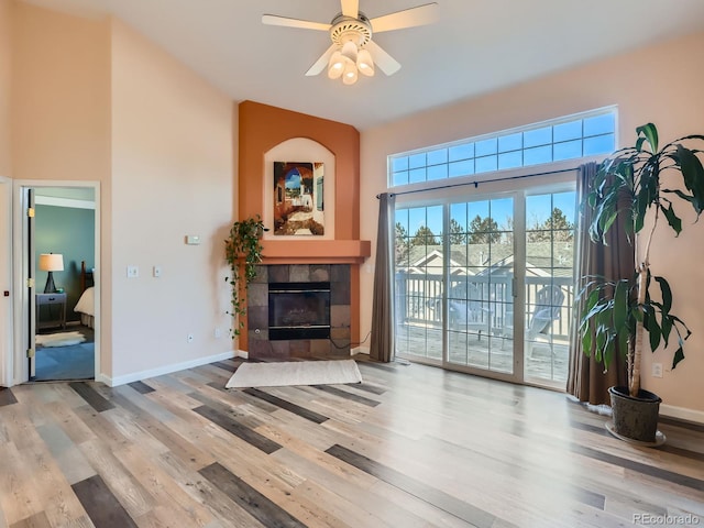 living room featuring ceiling fan, a tile fireplace, and light hardwood / wood-style flooring