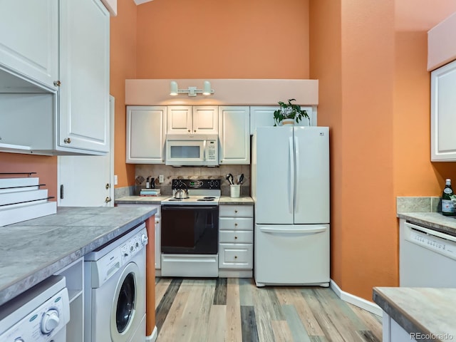 kitchen with light hardwood / wood-style flooring, white cabinets, white appliances, and washer / dryer