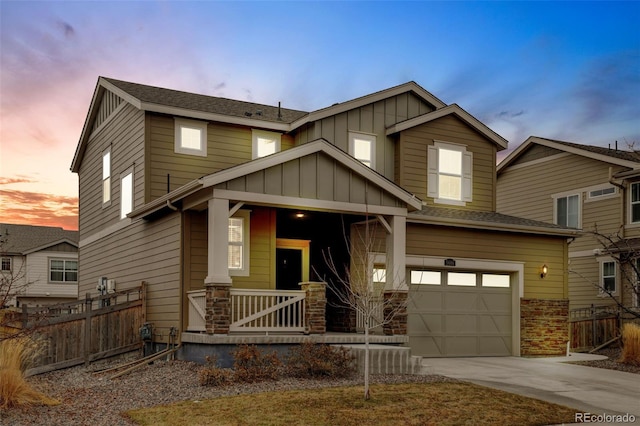 craftsman-style home featuring covered porch, concrete driveway, an attached garage, board and batten siding, and fence