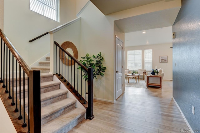 stairway featuring recessed lighting, wood finished floors, a wealth of natural light, and baseboards