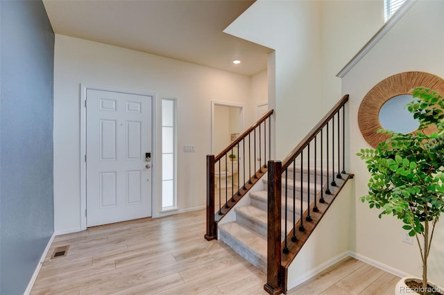 entryway with baseboards, visible vents, and light wood finished floors