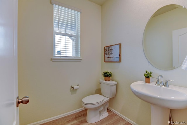 bathroom with toilet, a sink, baseboards, and wood finished floors