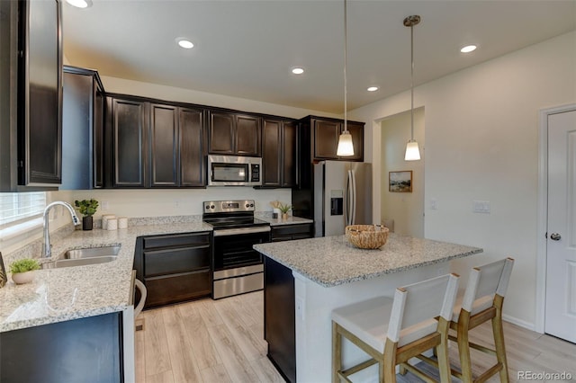 kitchen featuring light wood finished floors, dark brown cabinets, appliances with stainless steel finishes, and a sink