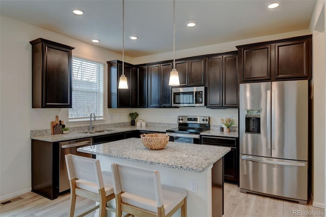 kitchen with visible vents, light wood-style flooring, stainless steel appliances, dark brown cabinets, and a sink