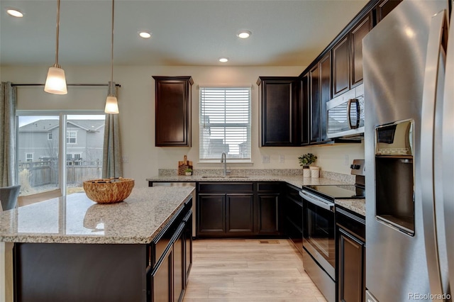 kitchen featuring stainless steel appliances, a sink, dark brown cabinetry, and light stone countertops