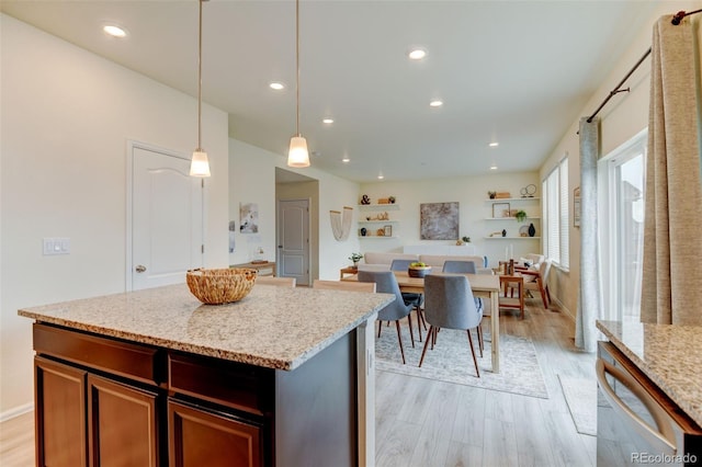 kitchen featuring light wood-type flooring, light stone countertops, dishwasher, and decorative light fixtures