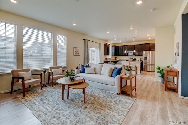 living room with light wood-style floors, recessed lighting, and baseboards