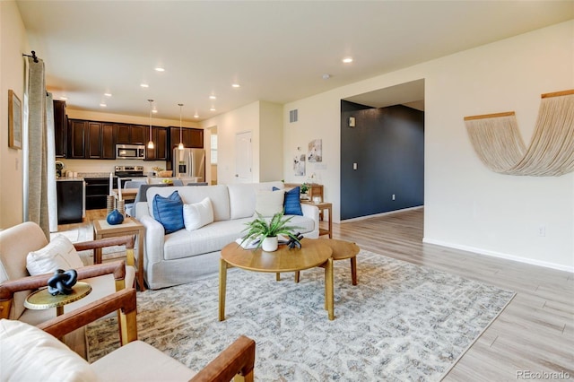 living room featuring light wood-type flooring, baseboards, visible vents, and recessed lighting