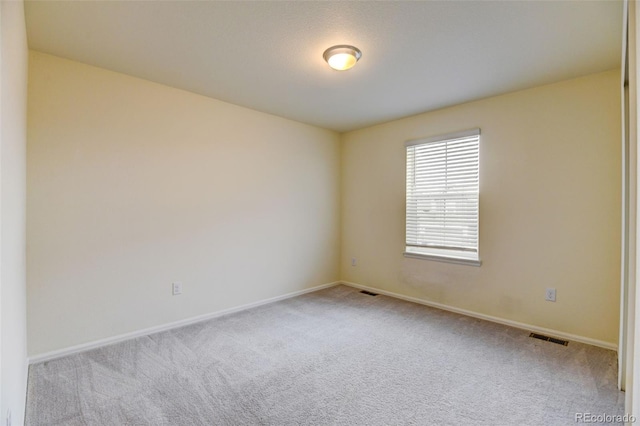 unfurnished room featuring baseboards, visible vents, and carpet flooring