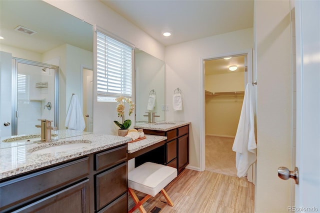 full bathroom with a stall shower, a walk in closet, visible vents, and a sink