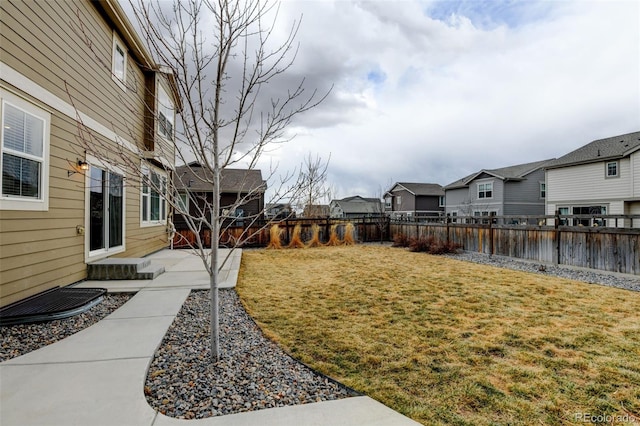 view of yard with a water view, a fenced backyard, and a residential view