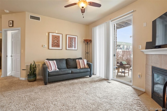 carpeted living room featuring ceiling fan and a tile fireplace