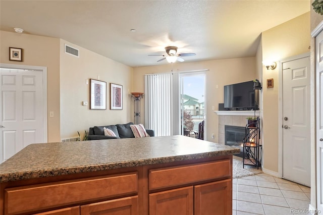 kitchen featuring ceiling fan, light tile patterned floors, and a fireplace