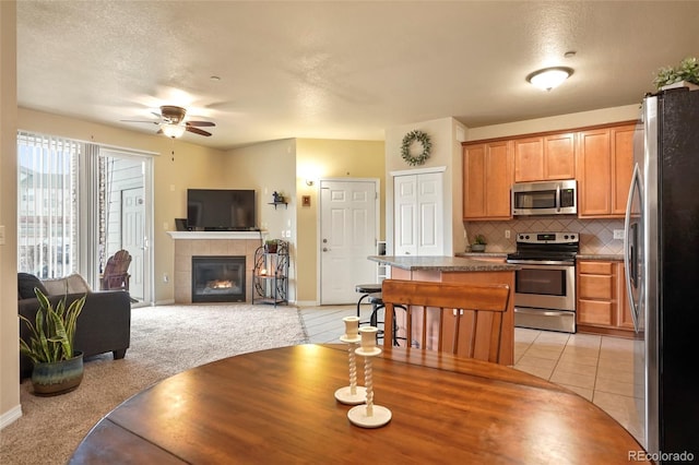 carpeted dining area featuring ceiling fan and a tile fireplace