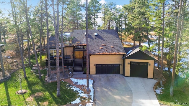 view of front facade featuring a chimney, stairway, concrete driveway, and a front yard