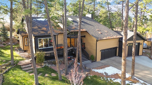 view of front of property featuring stairs, a tiled roof, a chimney, and a garage