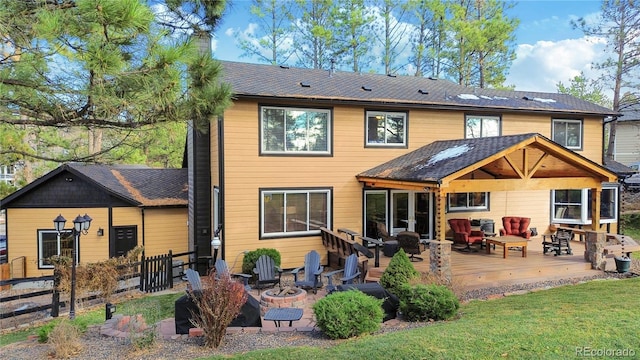 back of house with an outdoor fire pit, a shingled roof, a chimney, fence, and a wooden deck