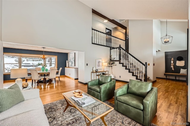 living area with stairs, a notable chandelier, and wood finished floors