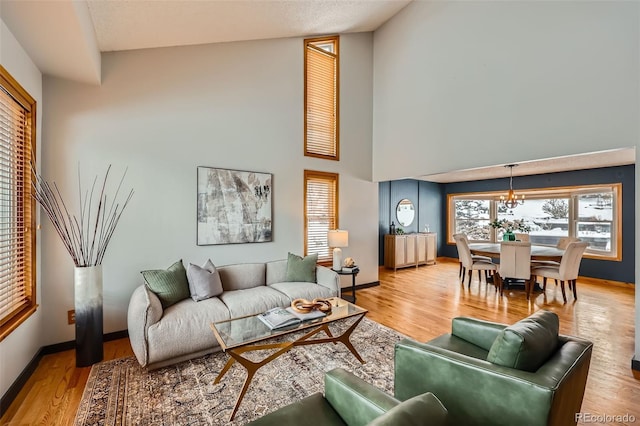 living room featuring a chandelier, wood finished floors, a towering ceiling, and baseboards