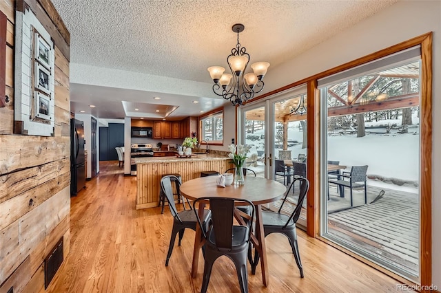 dining area with light wood-style floors, a chandelier, visible vents, and a textured ceiling