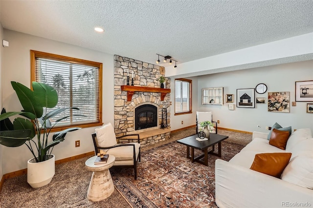 living room with carpet, a fireplace, a textured ceiling, track lighting, and baseboards