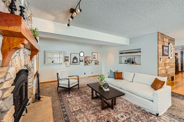 living area featuring carpet, a fireplace, a textured ceiling, and baseboards