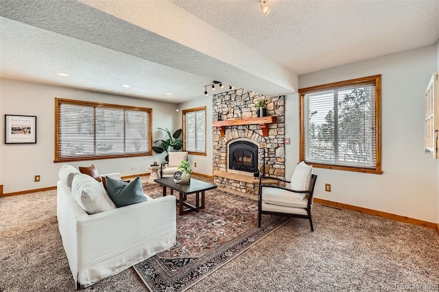 carpeted living room featuring rail lighting, a fireplace, baseboards, and a textured ceiling