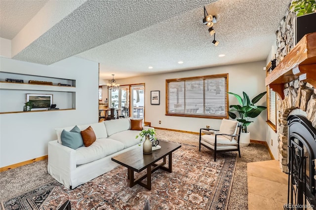 living area with a fireplace, an inviting chandelier, a textured ceiling, track lighting, and baseboards