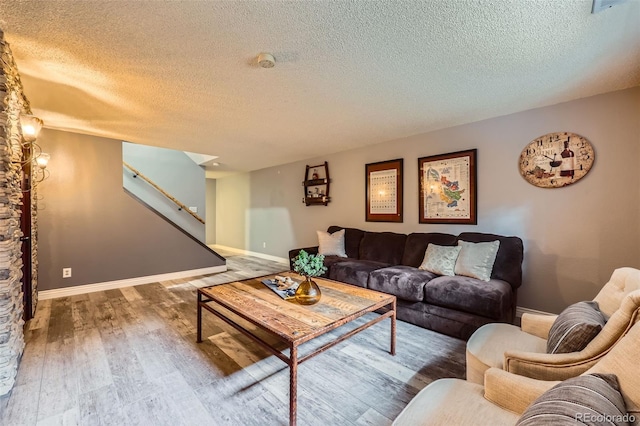 living area featuring a textured ceiling, stairway, wood finished floors, and baseboards