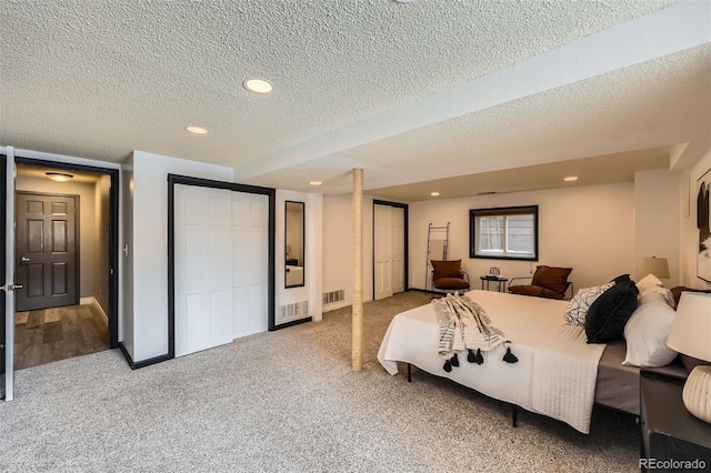 bedroom featuring visible vents, a textured ceiling, carpet floors, two closets, and recessed lighting