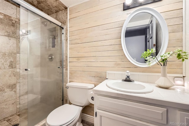 bathroom with a stall shower, vanity, toilet, and wooden walls