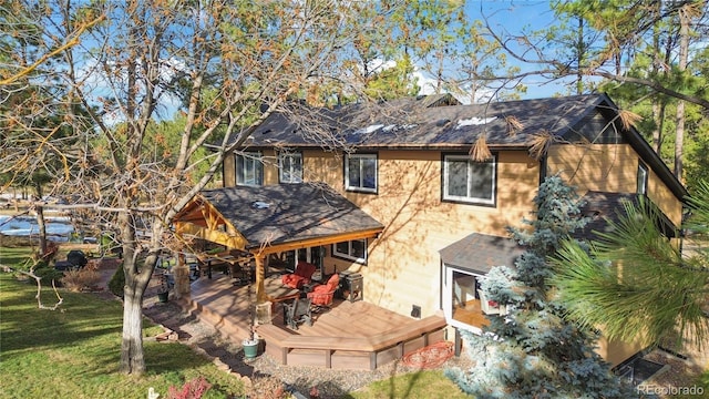 rear view of property with a yard, roof with shingles, and a wooden deck