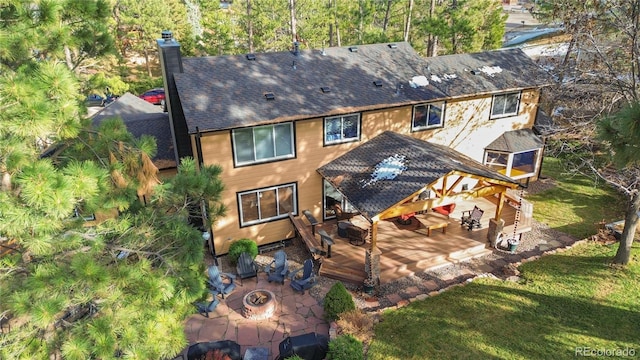 back of property with a patio, a fire pit, a lawn, a wooden deck, and a chimney