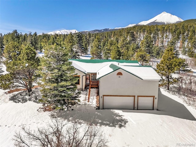 4860 County Road 140, Westcliffe, CO 81252 - view of front of home featuring a mountain view, a view of trees, stucco siding, and a garage