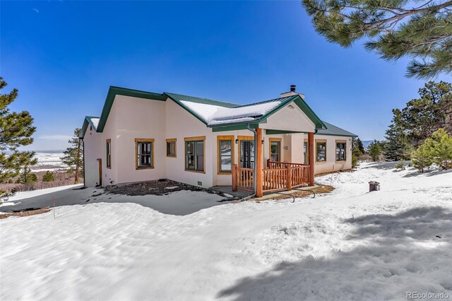 4860 County Road 140, Westcliffe, CO 81252 - snow covered rear of property with stucco siding, a chimney, and metal roof