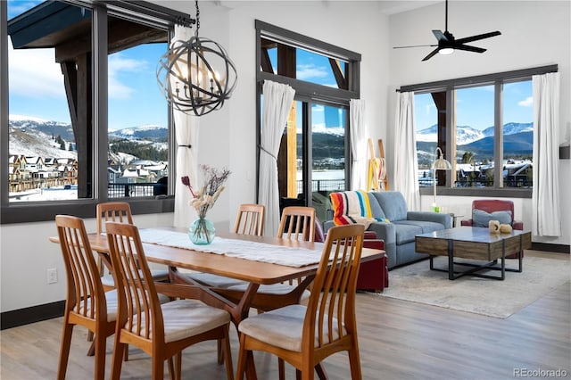 dining space featuring a mountain view, ceiling fan with notable chandelier, and light hardwood / wood-style floors