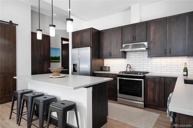 kitchen with a center island, a kitchen bar, a barn door, and appliances with stainless steel finishes