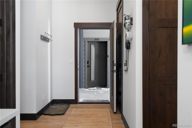 corridor featuring elevator and light hardwood / wood-style flooring