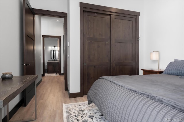 bedroom featuring ensuite bathroom, light hardwood / wood-style floors, and a closet