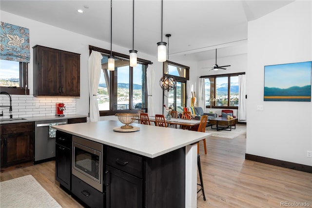 kitchen with sink, a breakfast bar area, stainless steel appliances, a center island, and decorative backsplash