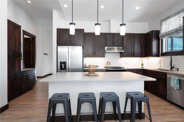 kitchen featuring a breakfast bar, sink, a center island, pendant lighting, and stainless steel appliances