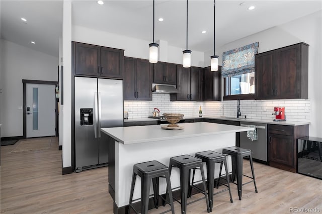 kitchen with pendant lighting, sink, appliances with stainless steel finishes, a center island, and a kitchen bar