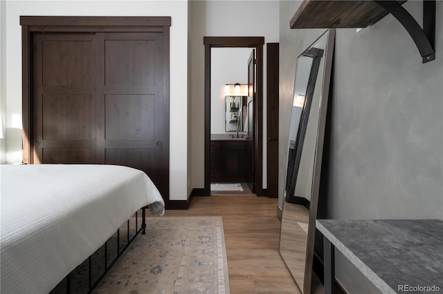 bedroom featuring connected bathroom and light hardwood / wood-style flooring