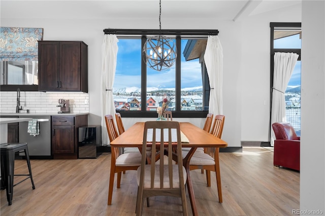 dining space featuring sink, a chandelier, and light wood-type flooring