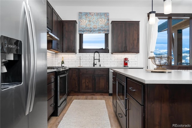 16 Springview Ln Unit A 304, Fraser, CO 80442 - kitchen with appliances with stainless steel finishes, a sink, light wood-type flooring, dark brown cabinetry, and backsplash
