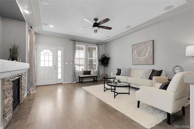 living room with a ceiling fan, wood finished floors, a stone fireplace, recessed lighting, and baseboards