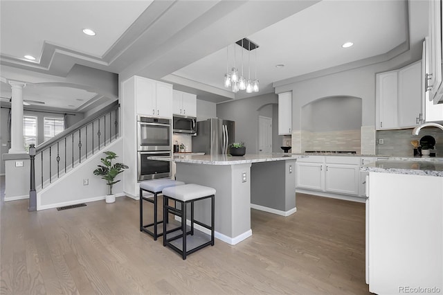 kitchen with stainless steel appliances, a sink, a kitchen island, dark wood-style floors, and a breakfast bar area
