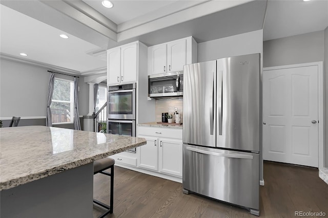 kitchen featuring stainless steel appliances, light stone countertops, white cabinets, dark wood-type flooring, and recessed lighting