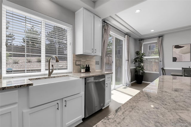 kitchen with dishwasher, a sink, light stone countertops, white cabinets, and healthy amount of natural light