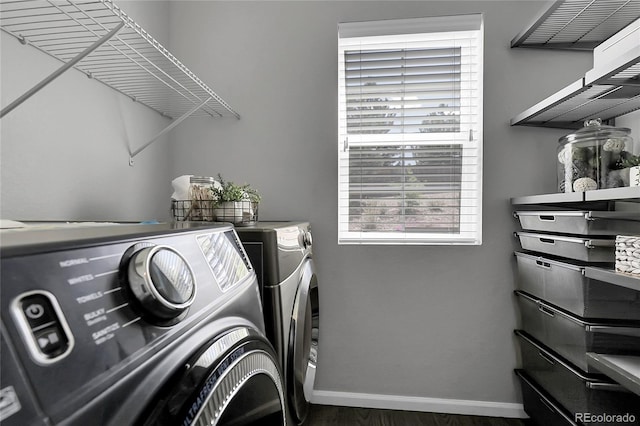 laundry room featuring washer and clothes dryer, baseboards, and wood finished floors